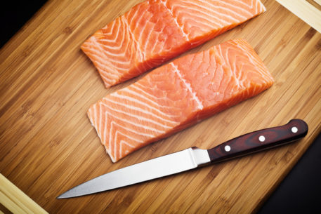 salmon fillet with knife on wood board