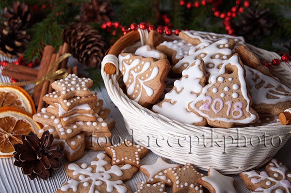 На фото имбирное новогоднее печенье украшенное глазурью и с новогодней декорацией