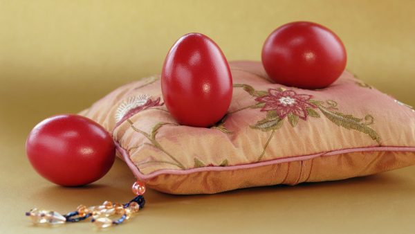 Три бордовых яйца на декоративной подушке
