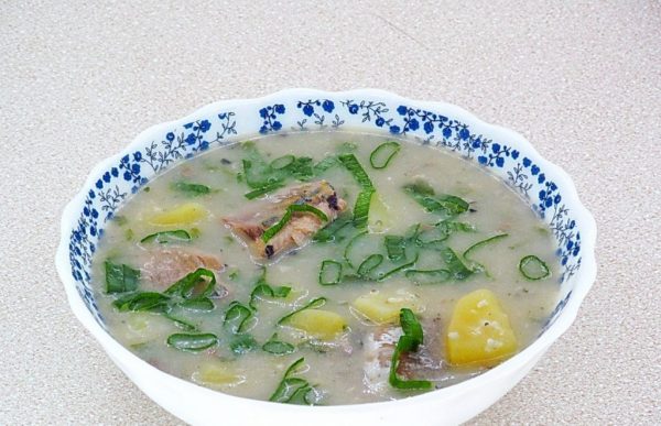 Рыбный суп с пшеном, картофелем и рубленым зелёным луком в тарелке