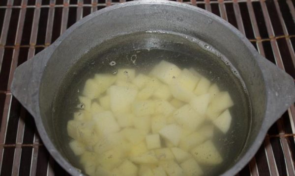 Нарезанный кубиками сырой картофель в кастрюле с водой