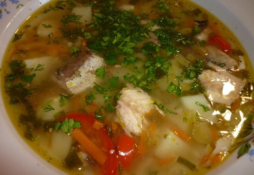 Рыбный суп с рисом, овощами и зеленью в тарелке