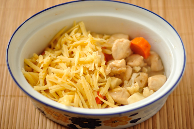 Процесс сборки пирога Слой курицы с овощами посыпан тертым сыром
