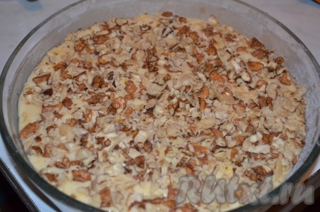 Выложить тесто в смазанную маслом и посыпанную мукой форму, сверху посыпать измельченными орешками, слегка вдавить их в тесто ложкой.