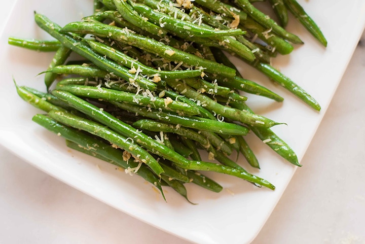 Horizontal image of the garlic parmesan green beans. Close up to show texture and grated parmesan.
