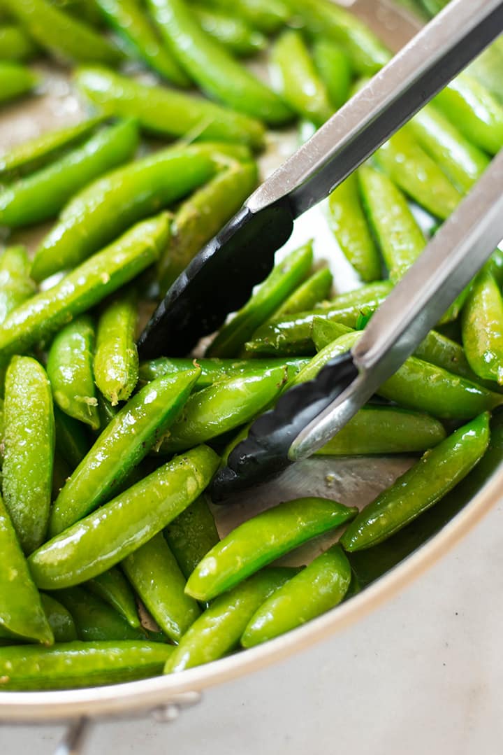 Close up of the sugar snap peas in the pan while being sauteed.