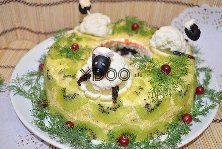 готовый салат Малахитовый браслет, украшенный веточками укропа, клюквой и овечками из цветной капусты и маслин