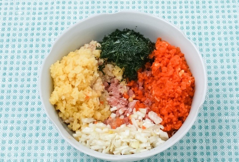 глубокая тарелка с измельченной свежей зеленью, вареной картошкой, морковью, луком и мясным фаршем