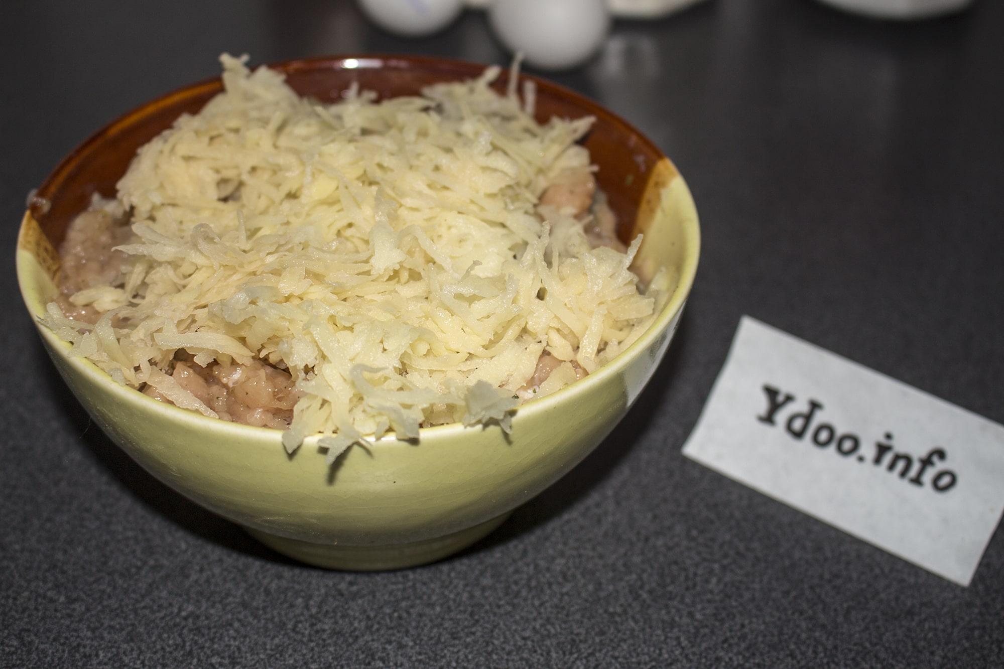 тертый сырой картофель с фаршем в глубокой тарелке на столе