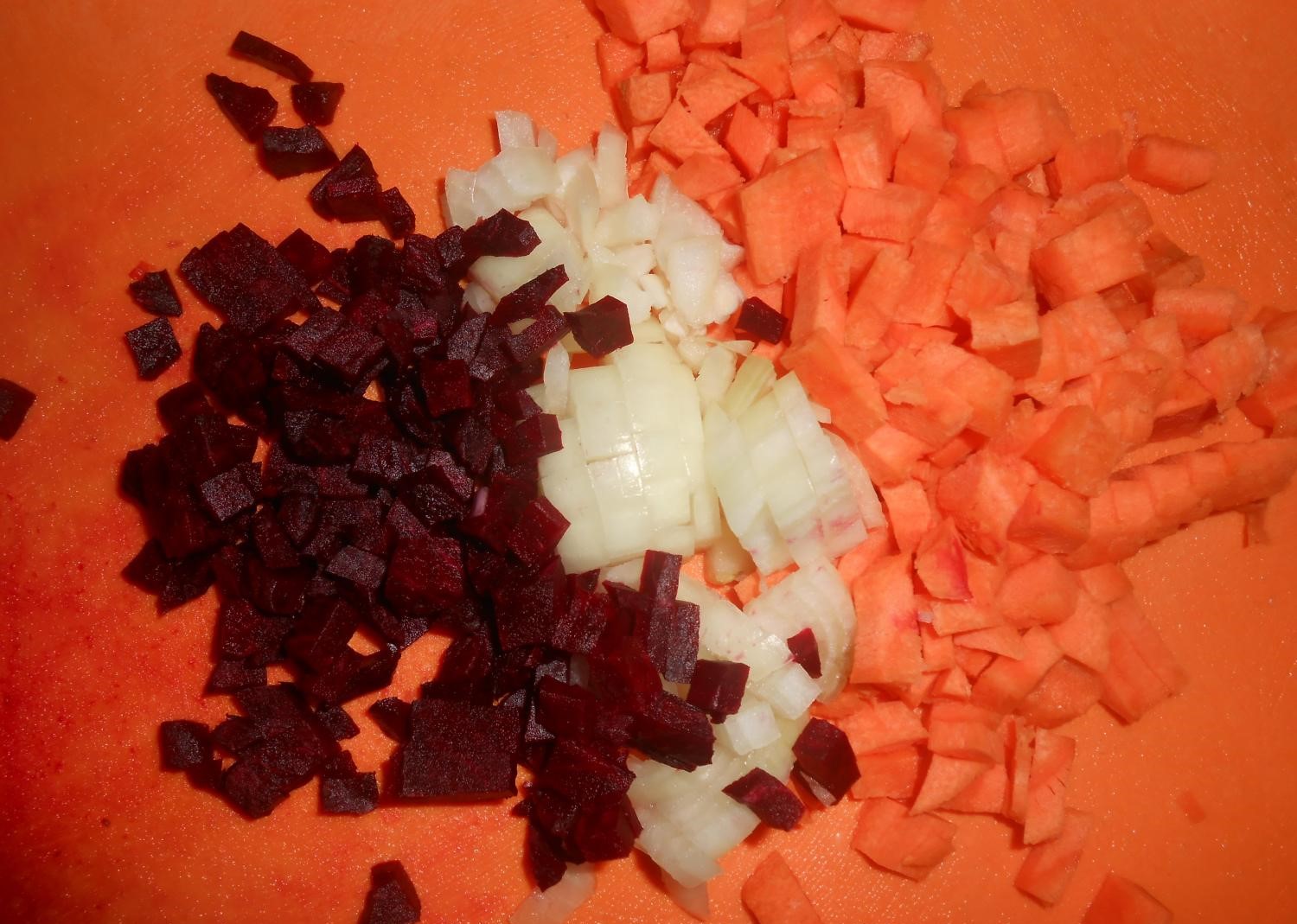 нарезанные кубиками свекла, репчатый лук и морковь на оранжевой разделочной доске