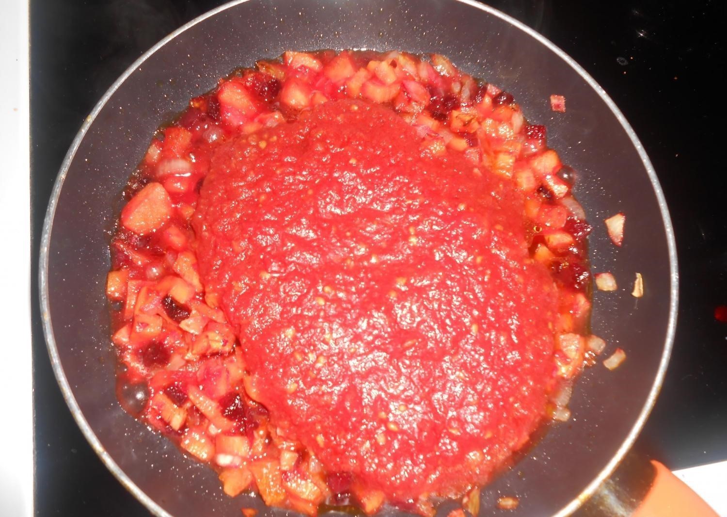 овощная зажарка, политая томатным соусом, в сковороде на плите